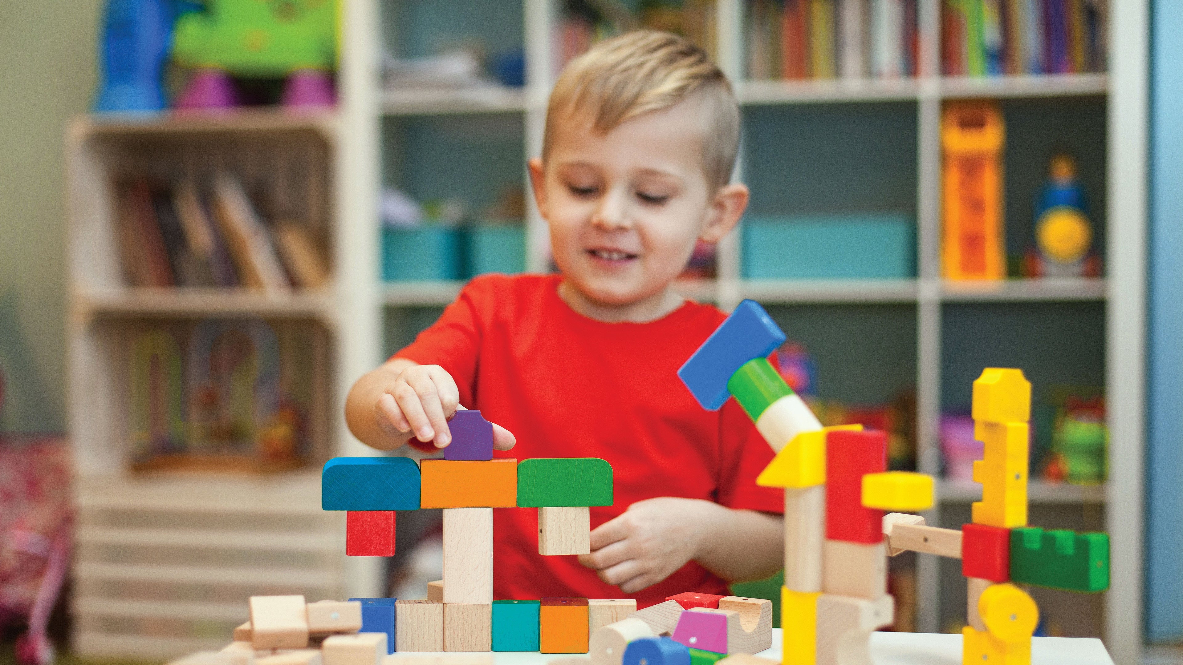 Child playing with colorful building blocks in a room with shelves in the background